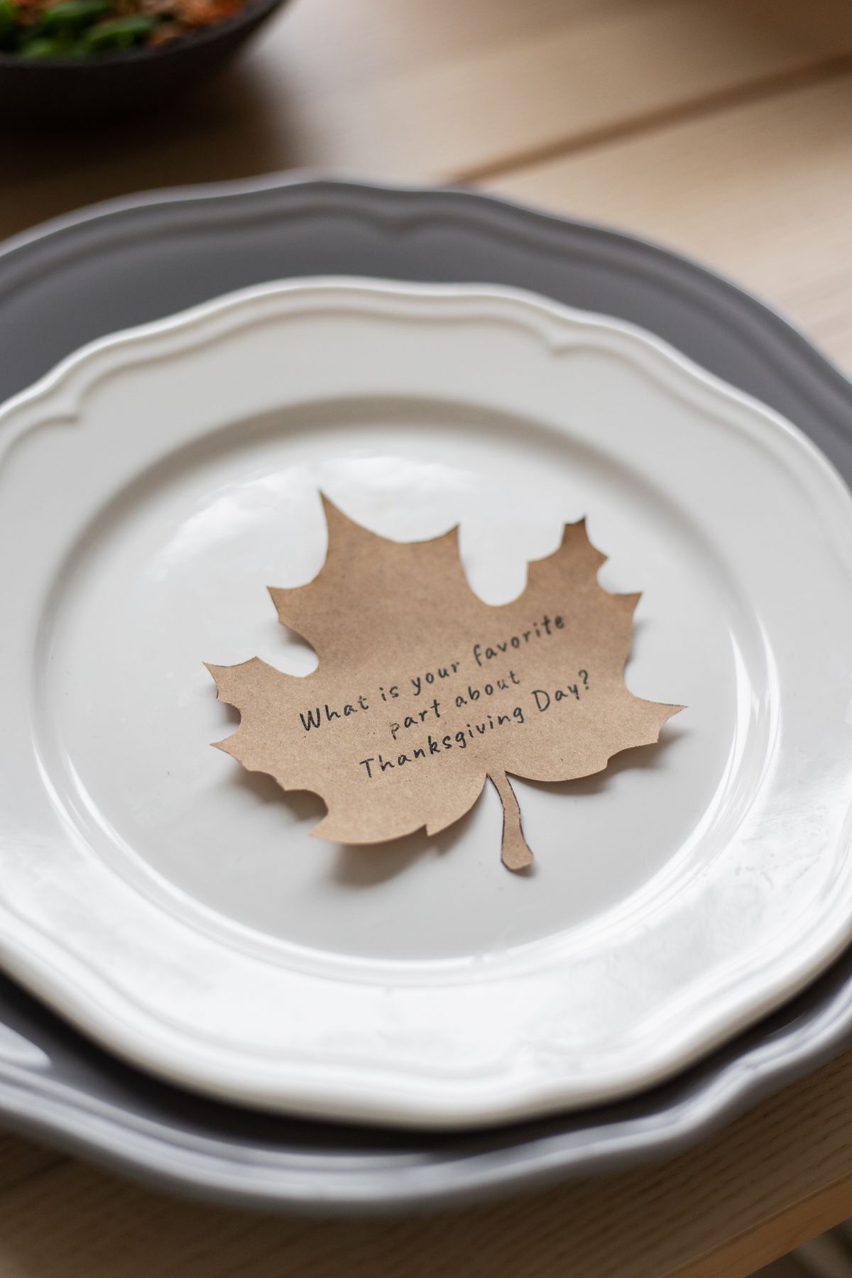 Maple leaf place card on a plate at a Thanksgiving table