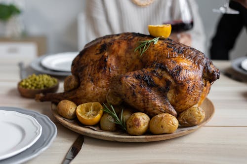Free From above of big turkey roasted with lemon and potatoes on round wooden tray placed on table for celebrating Thanksgiving Day Stock Photo