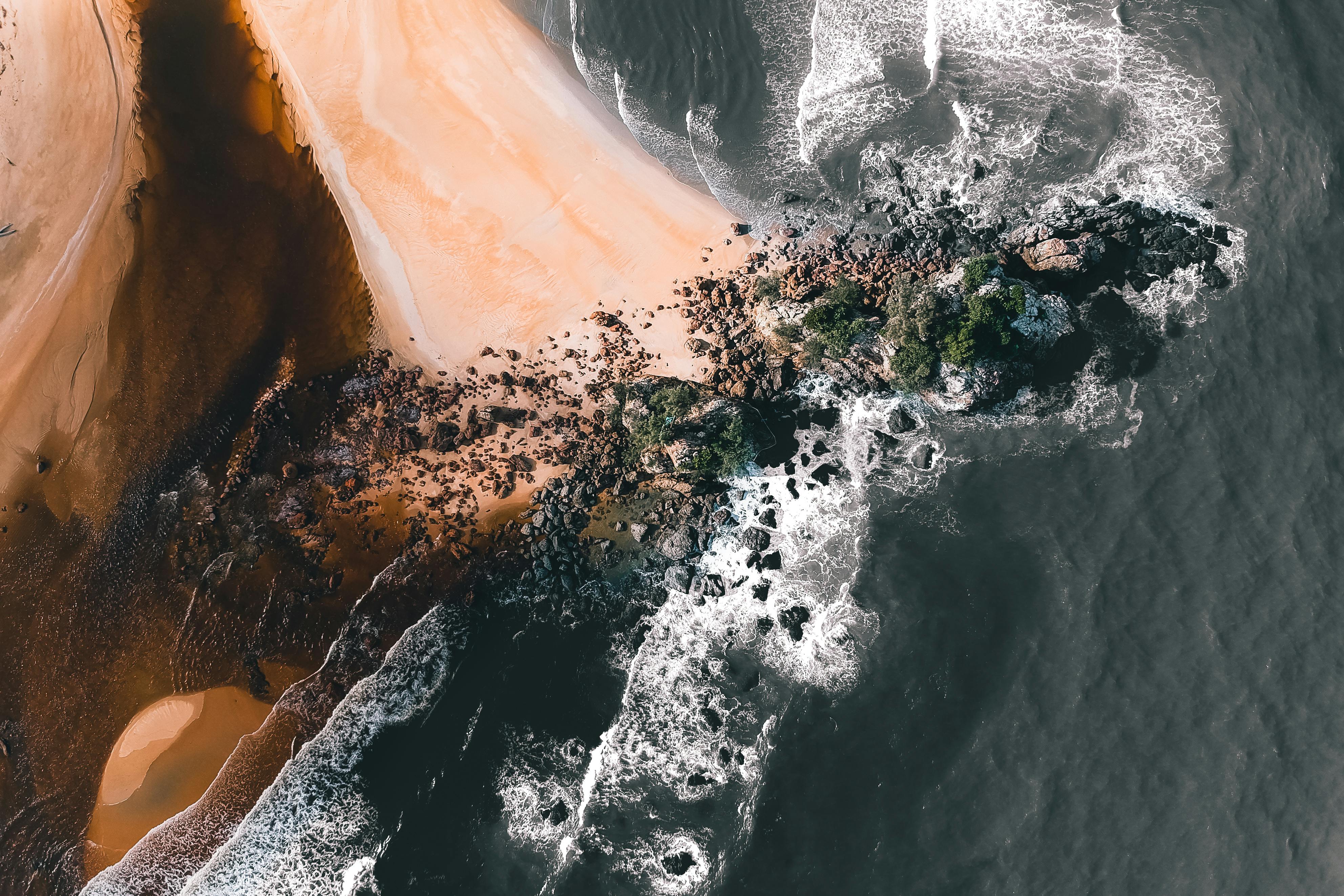 foamy sea and sandy beach with stones