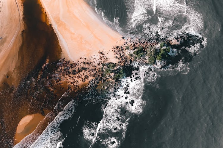 Foamy Sea And Sandy Beach With Stones