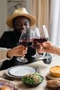 Crop cheerful diverse friends clinking glasses while having dinner