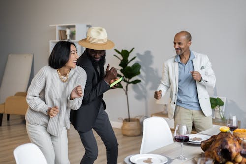 Positive diverse friends dancing while celebrating Thanksgiving