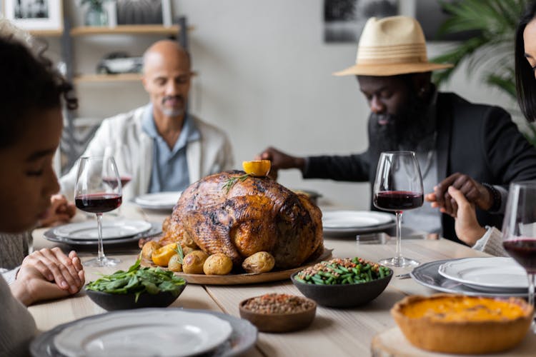 Diverse Friends Praying Before Having Thanksgiving Dinner