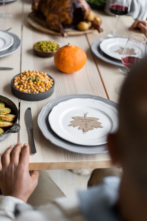 Free From above of blurred crop male sitting at wooden table served with roasted turkey and other meals prepared for celebrating Thanksgiving Stock Photo