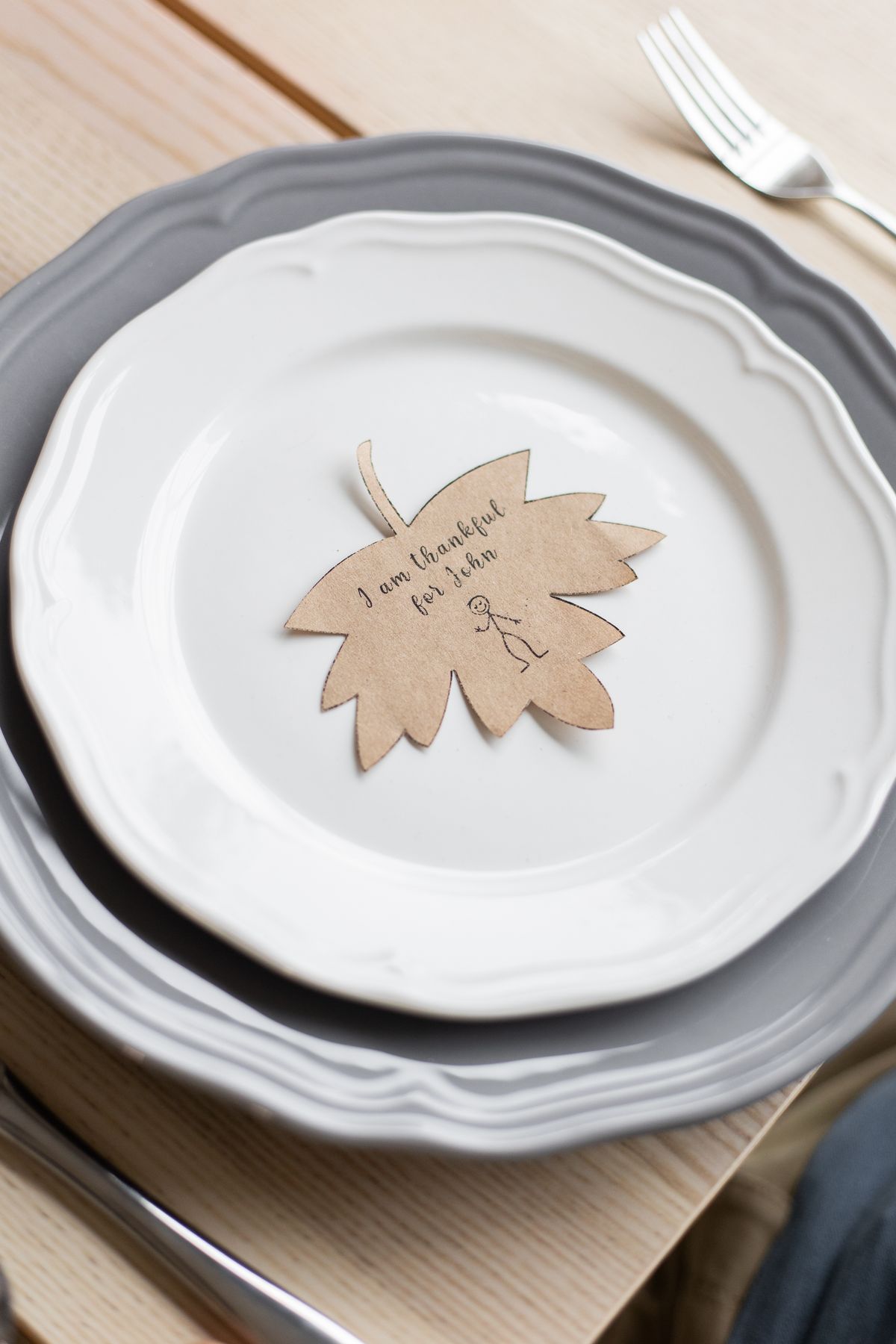 A Thanksgiving table setting with a paper maple leaf placemat a child made