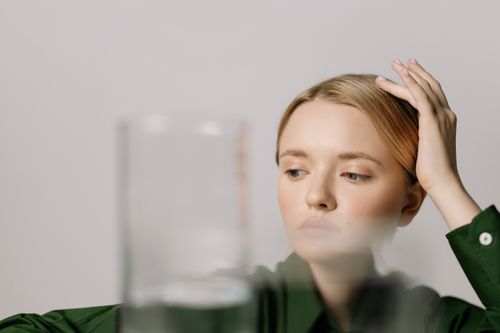 Free Woman contemplating with a glass of water in foreground, serene setting. Stock Photo