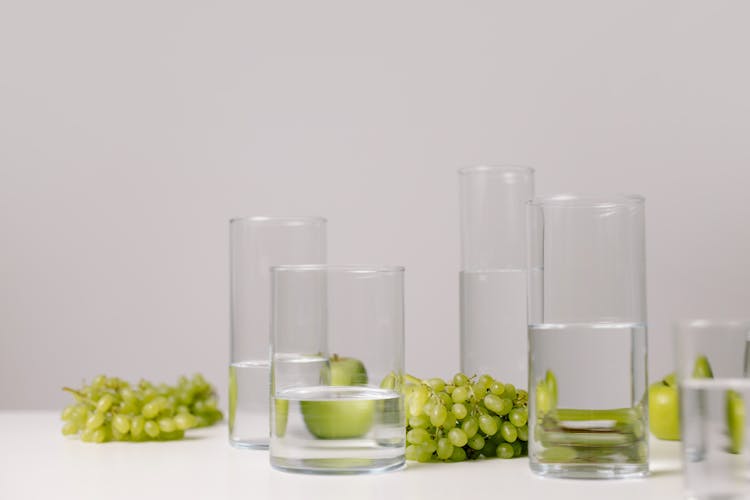 Grapes And Apples Among Glasses Of Water