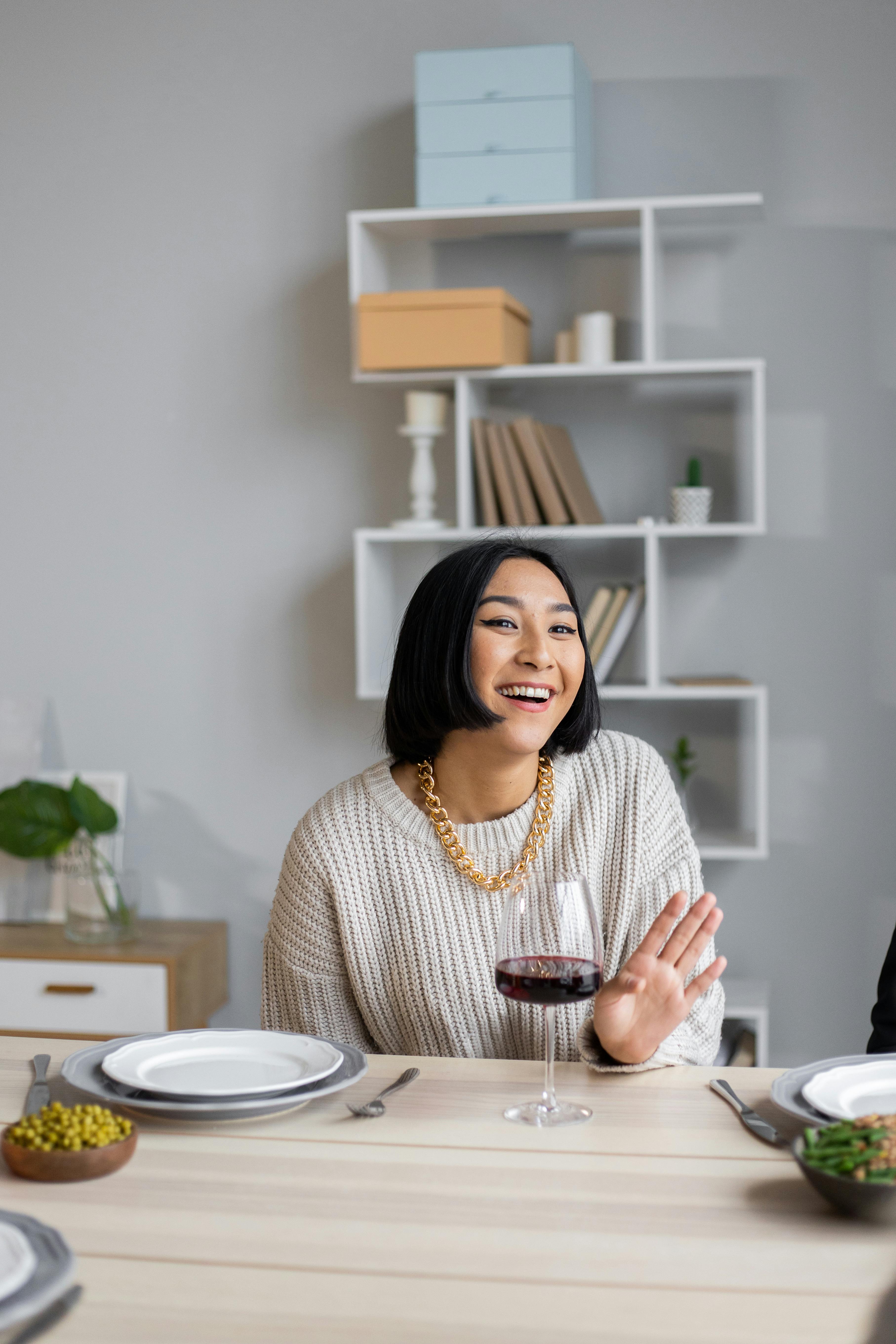 smiling ethnic woman at table with glass of wine