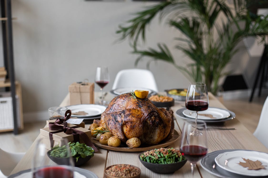 Free From above of palatable roasted turkey and glasses of wine on wooden table served for celebrating Thanksgiving Stock Photo