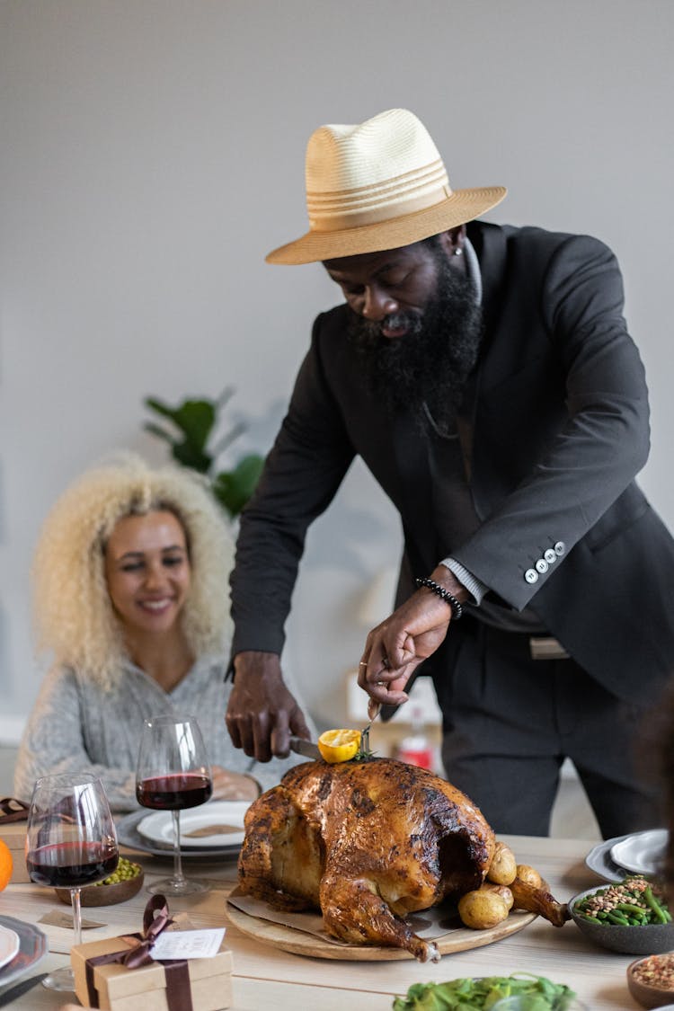 Delighted Black Man Cutting Turkey With Fork And Knife