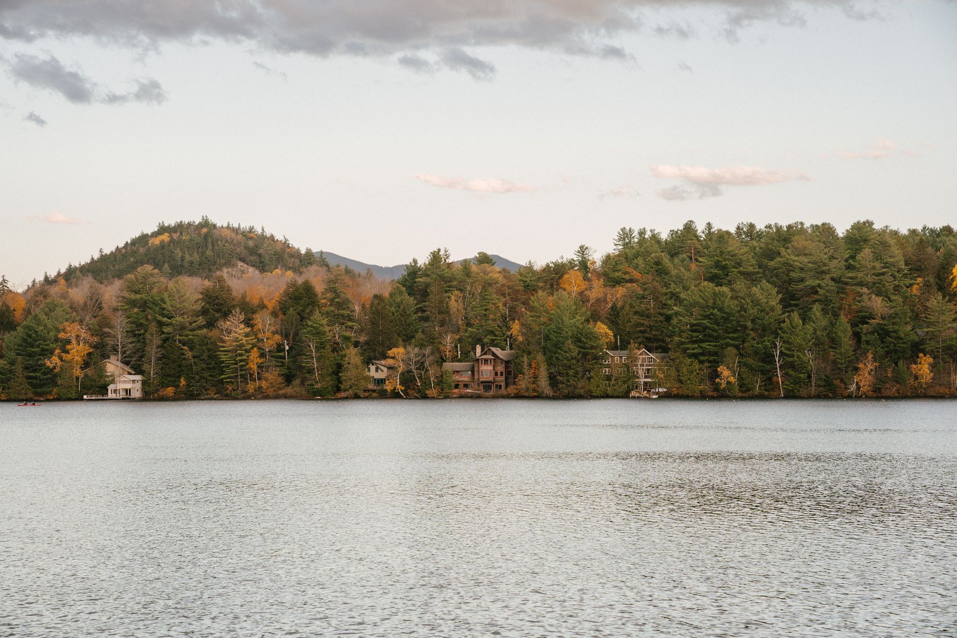 Picturesque scenery of tranquil lake located near small settlement in fall forest in mountainous area