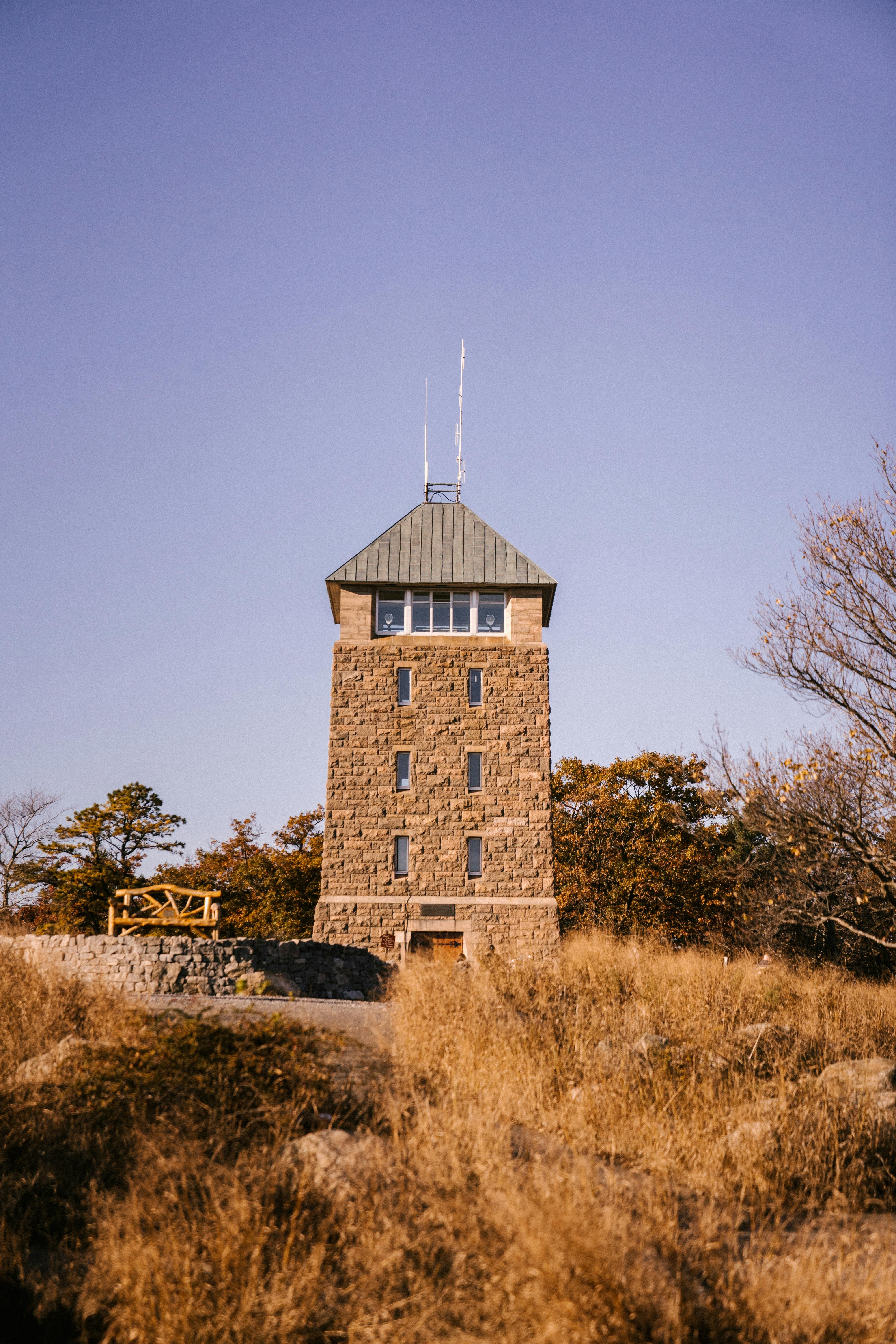 Exterior of old stone tower construction with shabby walls and windows located near autumn forest