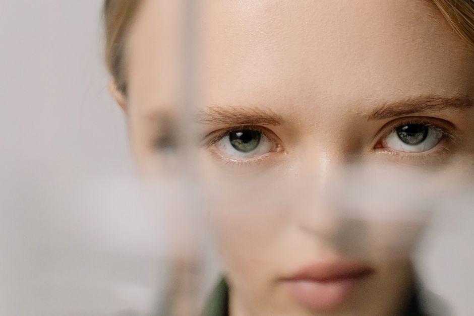 An artistic close-up portrait highlighting a woman's captivating eyes through glass.