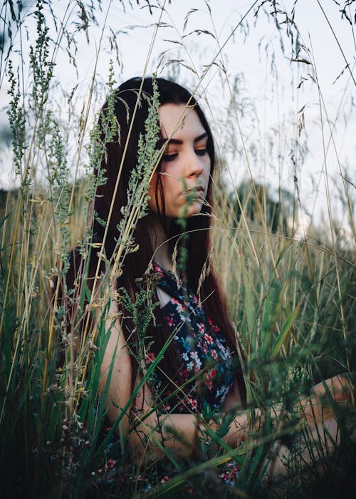 A Woman in Black and Red Floral Tank Top Standing on Green Grass Field