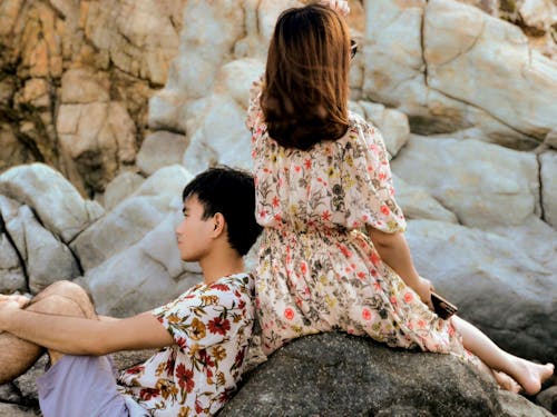 A Woman in Floral Dress Sitting on Rock