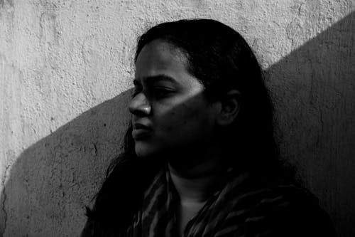 Grayscale Photo of Woman Near a Rough Wall