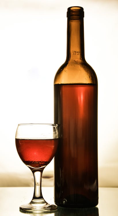 Glass of Wine Beside a Bottle of Wine · Free Stock Photo