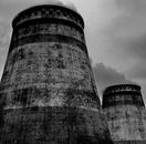 Old draft wet cooling towers in city industrial district on cloudy sky