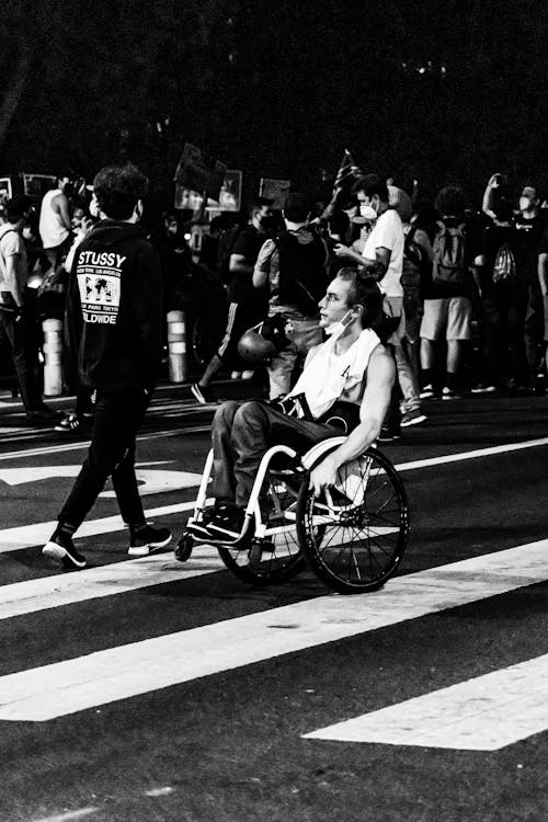 Free A Grayscale Photo of Man on a Wheelchair on the Street Stock Photo