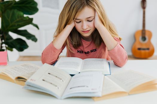 一名年轻女子穿着粉红色毛衣，正坐在室内的桌子上聚精会神地读书