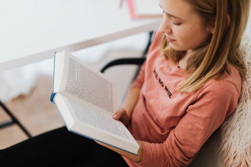 Woman in Pink Long Sleeve Shirt Reading a Book