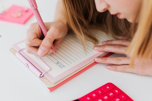 A woman concentrating while writing notes on a clipboard with a pink pen.
