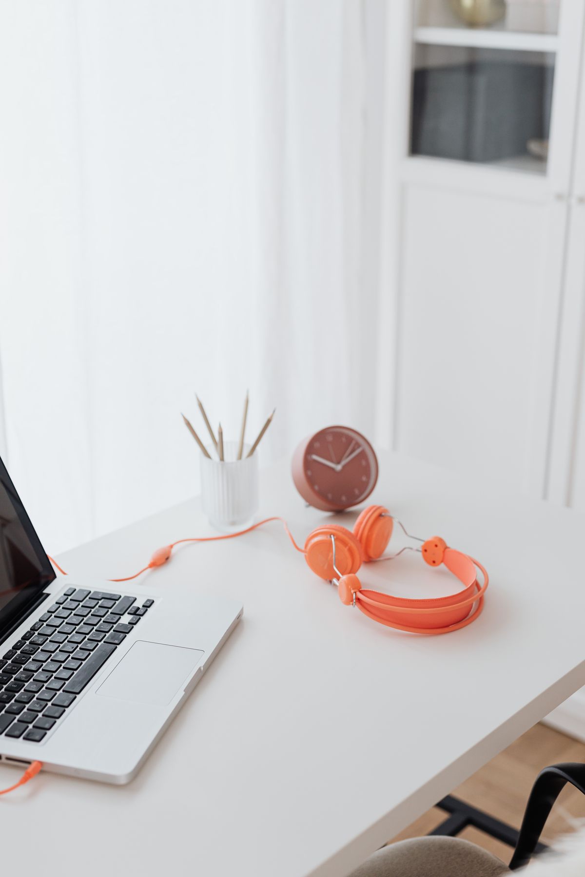 Orange headphones beside a laptop on a tidy desk