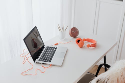 Free Laptop and Orange Headphones on a Desk  Stock Photo