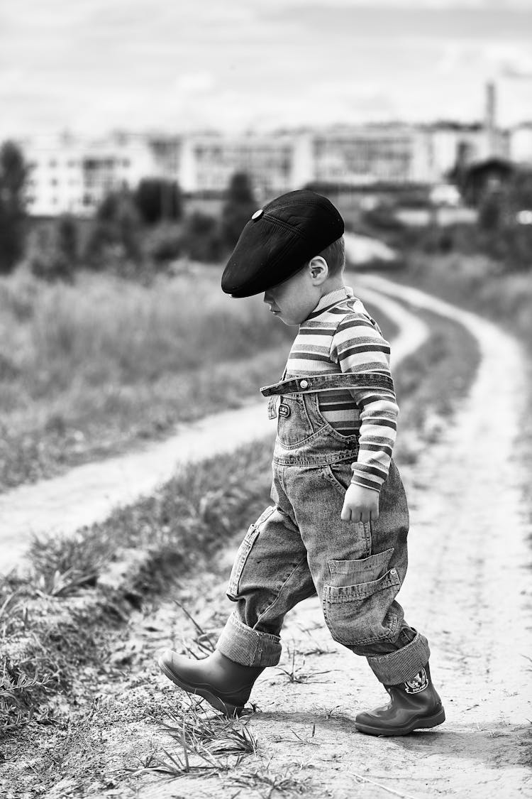 Grayscale Photo Of A Boy Crossing The Dirt Road 