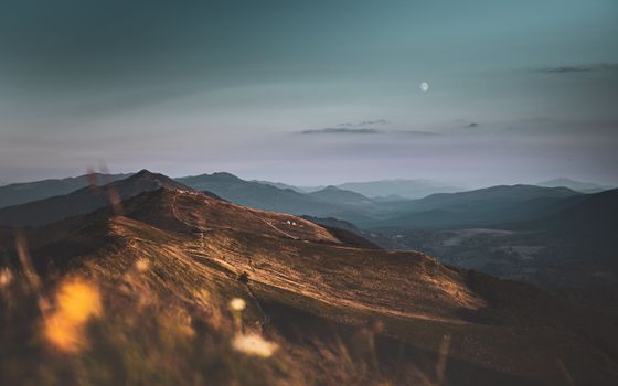 Captivating twilight view of Podkarpackie's rolling hills and distant moon.
