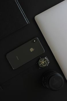 A sleek arrangement of gadgets including a smartphone, laptop, and wristwatch on a black surface, embodying modern technology.