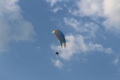 Free Experience the thrill of paragliding against a backdrop of a clear blue sky and white clouds. Stock Photo