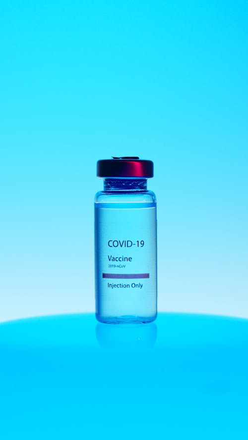Free A Close-Up View of a Covid-19 Vaccine Vial on Blue Background Stock Photo