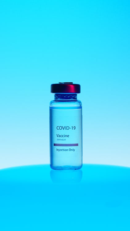 A Close-Up View of a Covid-19 Vaccine Vial on Blue Background