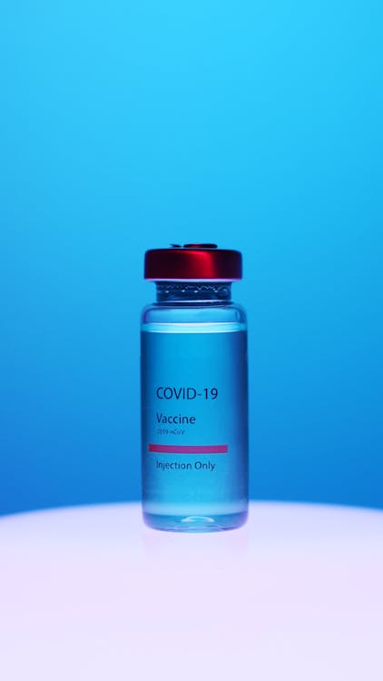 A Close-Up View of a Covid-19 Vaccine Vial on Blue Background