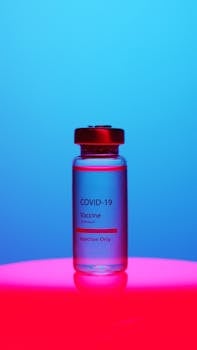 A COVID-19 vaccine vial on a vibrant blue and red background, symbolizing health and protection.