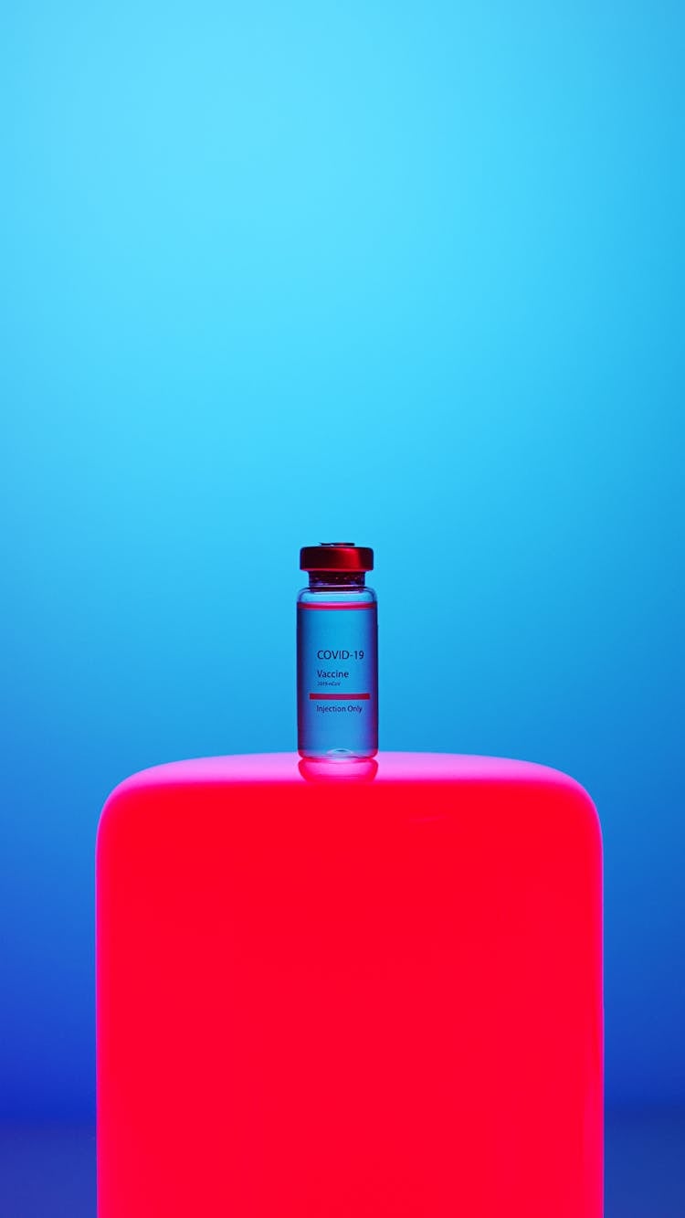 A Covid-19 Vaccine Vial On Blue Background