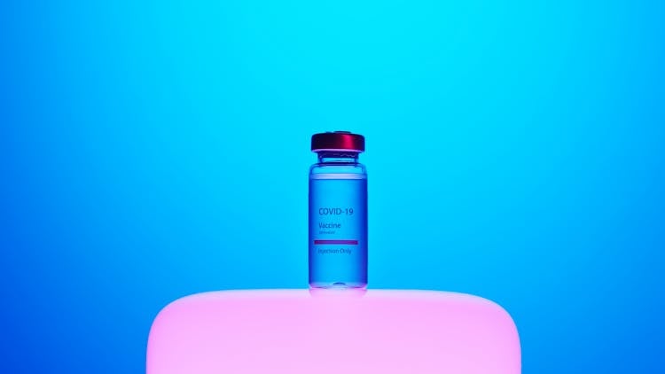 A Covid-19 Vaccine Vial On Blue Background