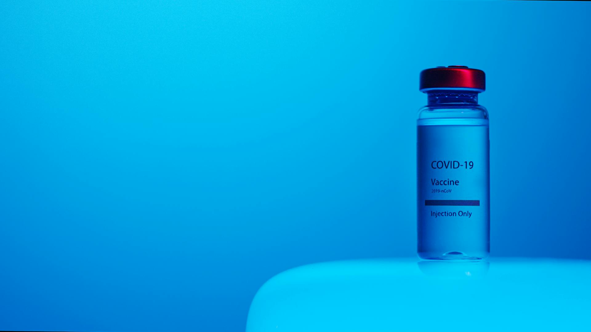 A Close-Up View of a Covid-19 Vaccine Vial on Blue Background