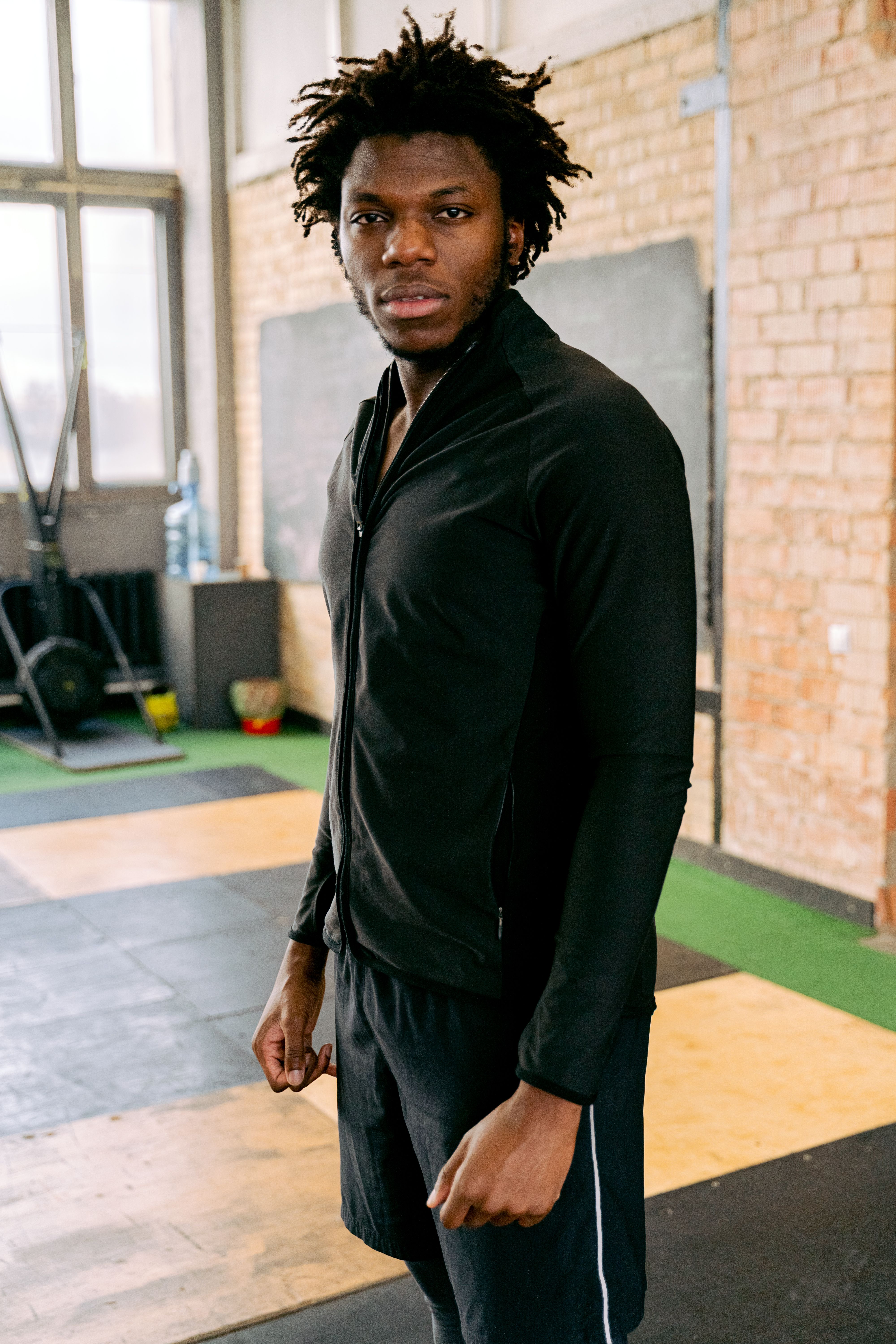 Portrait of a man in a fitness gym, wearing a black jacket, looking confident.