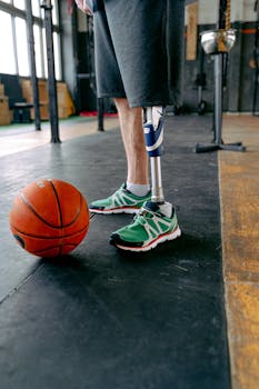 Close-up of athlete with prosthetic leg and basketball in a gym setting.