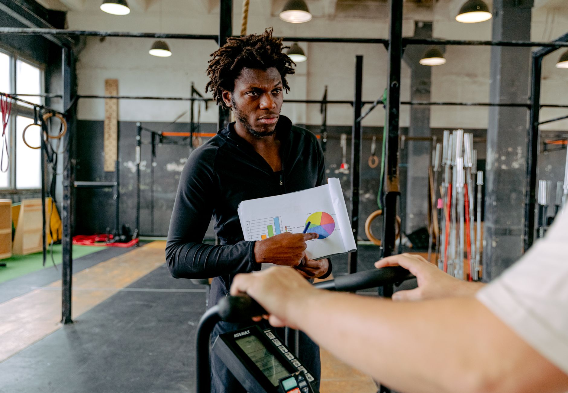 A personal trainer guides a client during a workout session at the gym.