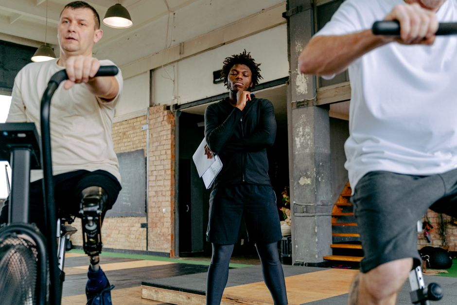 An inclusive fitness session featuring adults with prosthetic legs cycling under guidance.