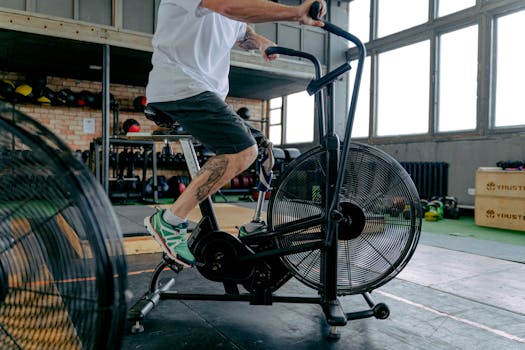 A determined man with a prosthetic leg working out on a stationary bike in a gym environment.
