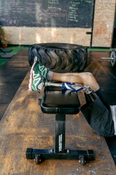 Adult male with prosthetic leg performing strength exercises on a bench at the gym.