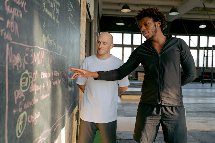 Personal Trainer Explaining An Exercise Plan To A Man 