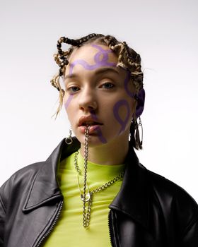 创意工作室的肖像描绘了一位女性，她拥有艺术面部彩绘、链条和独特发型