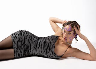 Woman in mini dress lying on floor and touching head