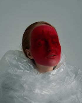 一位年轻、温柔、善于反思的女人，闭着眼睛，面容明亮，被装在一个皱巴巴的塑料袋里