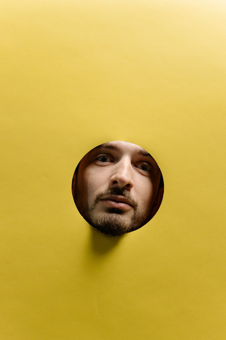 Man's Face On A Hole In A Yellow Surface